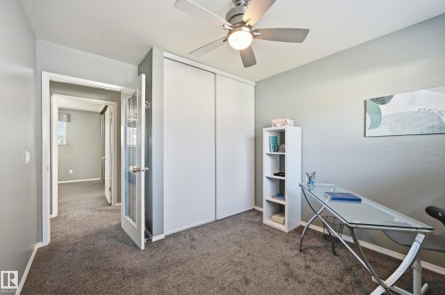 Carpeted flooring throughout, ceiling fan with integrated lighting, and white bi-fold closet doors - 10552 45 Street Nw, Edmonton, AB 