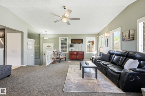 Spacious living area featuring a vaulted ceiling with a ceiling fan, numerous windows with blinds, and built-in wall sconces - 10552 45 Street Nw, Edmonton, AB 