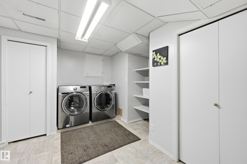 Laundry area featuring a drop ceiling, light-toned tiled flooring, and built-in shelving - 10552 45 Street Nw, Edmonton, AB 