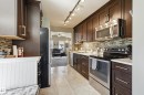 Kitchen featuring wood-finish cabinetry, stainless steel appliances, track lighting, a mosaic tile backsplash, and light-toned flooring - 10552 45 Street Nw, Edmonton, AB 
