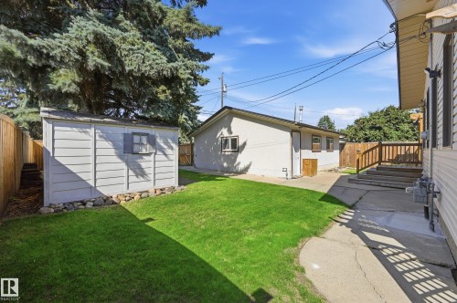 Manicured lawn, wood fencing, concrete patio, storage shed, and external wood staircase - 10552 45 Street Nw, Edmonton, AB 