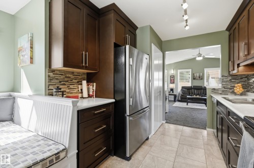 Kitchen featuring dark wood-finish cabinetry, white countertops, mosaic tile backsplash, stainless steel appliances, and built-in bench seating - 10552 45 Street Nw, Edmonton, AB 
