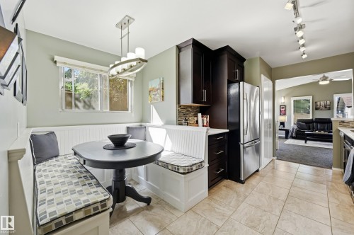 Built-in dining banquette, dark wood-finish cabinetry, stainless steel refrigerator, tile flooring, and track lighting - 10552 45 Street Nw, Edmonton, AB 