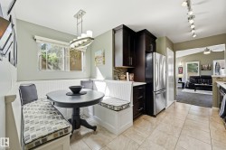 Built-in dining banquette, dark wood-finish cabinetry, stainless steel refrigerator, tile flooring, and track lighting - 