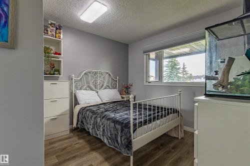 Spacious room with wood-finish flooring, a large window, and a built-in shelving unit with drawers - 7408 180 Street Nw, Edmonton, AB 