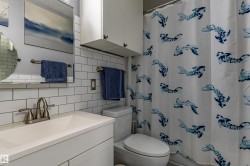White subway tile backsplash, white vanity with integrated sink, brushed nickel faucet, and white wall-mounted cabinetry - 