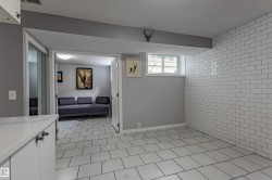 Subway tile accent wall, white tile flooring, white cabinetry with polished hardware, and a window providing natural illumination - 