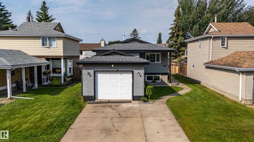 Contemporary exterior with an attached garage, paved driveway, and a curved concrete walkway - 7408 180 Street Nw, Edmonton, AB 