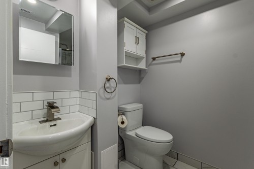 Bathroom featuring a pedestal sink, subway tile wainscoting, wall-mounted medicine cabinet, overhead storage, and a built-in toilet - 7408 180 Street Nw, Edmonton, AB 