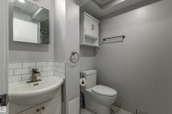 Bathroom featuring a pedestal sink, subway tile wainscoting, wall-mounted medicine cabinet, overhead storage, and a built-in toilet - 