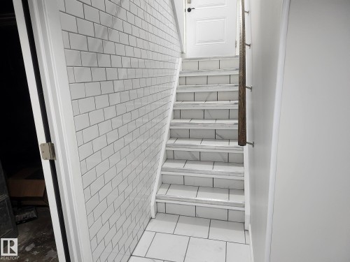 Subway tile wall, tile flooring, wood-finish handrail, paneled interior door, tiled stair treads - 7408 180 Street Nw, Edmonton, AB 