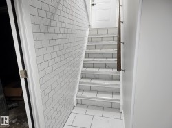 Subway tile wall, tile flooring, wood-finish handrail, paneled interior door, tiled stair treads - 