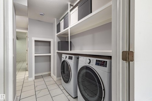 Built-in shelving, recessed wall niche, tile flooring, and integrated laundry appliances - 7408 180 Street Nw, Edmonton, AB 