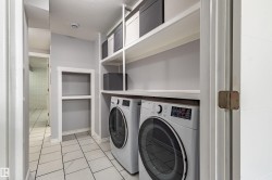 Built-in shelving, recessed wall niche, tile flooring, and integrated laundry appliances - 