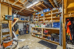 Exposed wood beam ceiling, comprehensive built-in shelving, integrated workbench, concrete flooring, and ample storage space - 