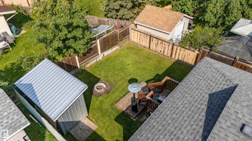 Expansive fenced backyard featuring a wood deck, manicured lawn, and two detached storage sheds - 7408 180 Street Nw, Edmonton, AB 