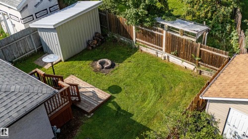 Expansive backyard retreat featuring a manicured lawn, mature landscaping, and wooden deck with seating area - 7408 180 Street Nw, Edmonton, AB 