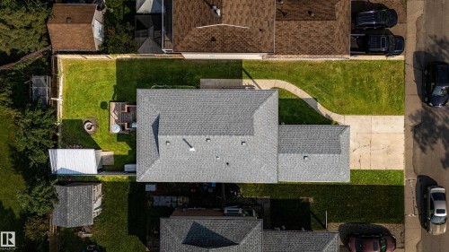 Expansive lot featuring a main residence with a gray shingle roof, a detached shed, a paved driveway, and a fenced backyard with a raised deck - 7408 180 Street Nw, Edmonton, AB 