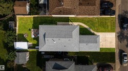 Expansive lot featuring a main residence with a gray shingle roof, a detached shed, a paved driveway, and a fenced backyard with a raised deck - 