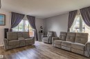 Spacious room featuring wood-finish flooring, light grey wall paint, and large windows with privacy drapery - 7408 180 Street Nw, Edmonton, AB 