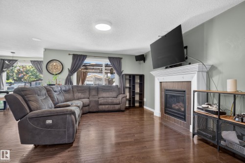 Wood-finish flooring, recessed lighting, and a fireplace with a white mantel and tile surround - 1332 72 Street Sw, Edmonton, AB 