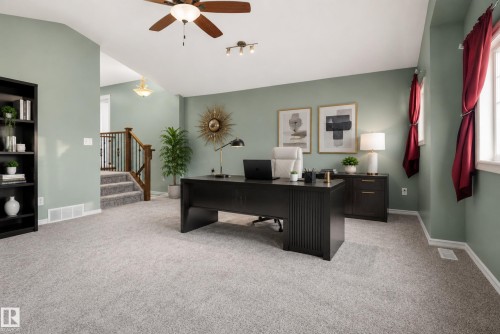 Plush carpeting, vaulted ceiling with ceiling fan, built-in shelving, staircase with wood railing and metal balusters, and track lighting - 1332 72 Street Sw, Edmonton, AB 