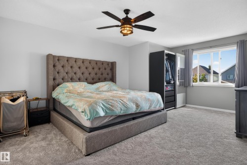 Plush carpeting, a ceiling fan with integrated lighting, and multiple windows with curtain rods - 1332 72 Street Sw, Edmonton, AB 