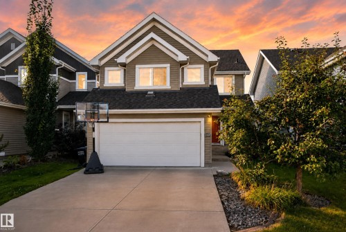 Gabled two-story exterior with horizontal siding and shingle accents, attached two-car garage, concrete driveway, and landscaped front yard - 1332 72 Street Sw, Edmonton, AB 