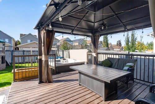 Expansive wood-finish deck featuring a gazebo with privacy curtains, built-in hot tub, and metal railing - 1332 72 Street Sw, Edmonton, AB 