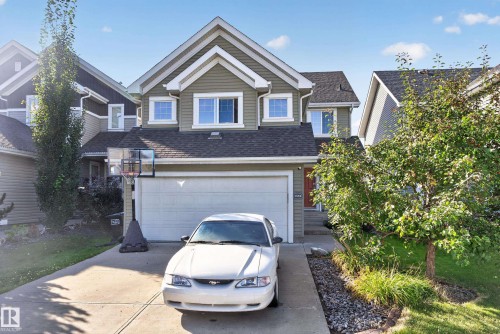 Two-story residence with a gabled roofline, attached two-car garage, concrete driveway, and front yard landscaping - 1332 72 Street Sw, Edmonton, AB 
