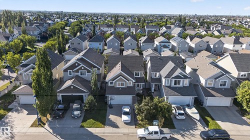 Residential street with mature trees and detached homes featuring attached garages - 1332 72 Street Sw, Edmonton, AB 