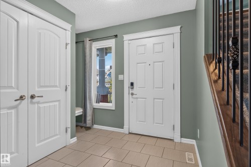 Welcoming foyer showcasing sage-green walls, ceramic tile flooring, and white six-panel doors with brushed nickel hardware - 1332 72 Street Sw, Edmonton, AB 