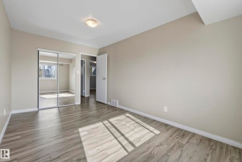 Wood-finish flooring throughout, light neutral wall tones, and mirrored closet doors - 141 Dickinsfield Court Nw, Edmonton, AB 