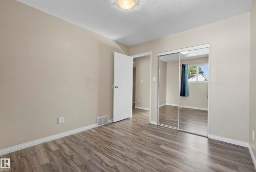 Wood-finish flooring, neutral wall tones, and mirrored closet doors - 141 Dickinsfield Court Nw, Edmonton, AB 