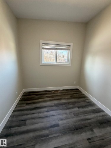 Neutral wall tones complemented by dark wood-finish flooring - 7604 7606 75 Street Nw, Edmonton, AB - Indoor Photo Showing Other Room