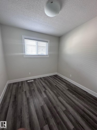 Bedroom with wood-finish flooring, crisp white baseboards, a single window, white window blinds, and a flush-mount ceiling light fixture - 7604 7606 75 Street Nw, Edmonton, AB - Indoor Photo Showing Other Room