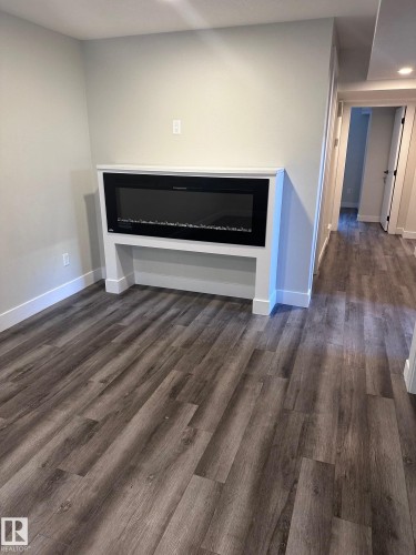 Modern linear electric fireplace with a white mantel and surround - 7604 7606 75 Street Nw, Edmonton, AB - Indoor With Fireplace