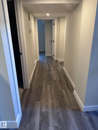 Hallway featuring wood-finish flooring, recessed lighting, white baseboards, and neutral wall paint - 7604 7606 75 Street Nw, Edmonton, AB - Indoor Photo Showing Other Room