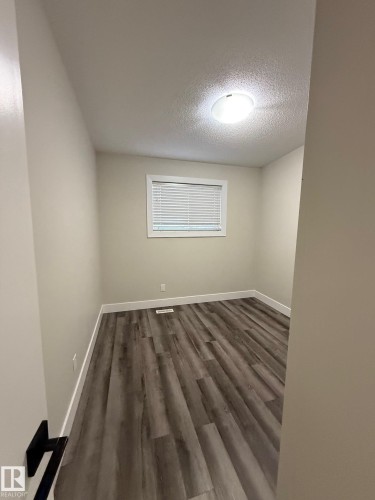 Room featuring wood-finish flooring, neutral wall tones, and crisp white trim - 7604 7606 75 Street Nw, Edmonton, AB - Indoor Photo Showing Other Room