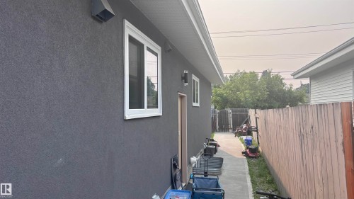 Grey stucco exterior with white-framed window and twin outdoor sconces - 7604 7606 75 Street Nw, Edmonton, AB - Outdoor With Exterior