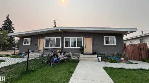 Duplex property featuring a dark gray stucco exterior, white window frames, and light-colored entry doors - 7604 7606 75 Street Nw, Edmonton, AB - Outdoor