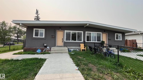 Duplex exterior featuring a gray stucco finish and contrasting white window frames - 7604 7606 75 Street Nw, Edmonton, AB - Outdoor