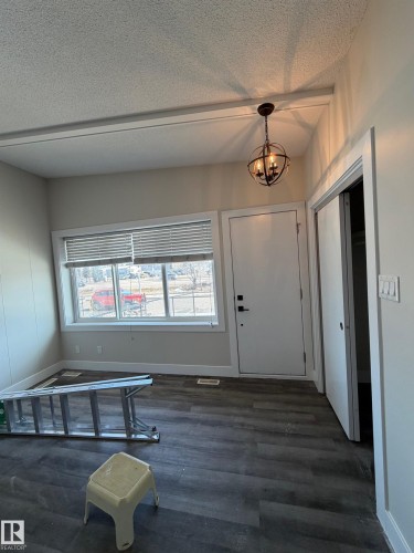 Entry area featuring dark wood-finish flooring, white trim, and a contemporary orb chandelier - 7604 7606 75 Street Nw, Edmonton, AB - Indoor Photo Showing Other Room