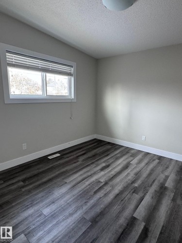 Interior room featuring dark wood-finish flooring, light-colored walls, and a white baseboard trim - 7604 7606 75 Street Nw, Edmonton, AB - Indoor Photo Showing Other Room