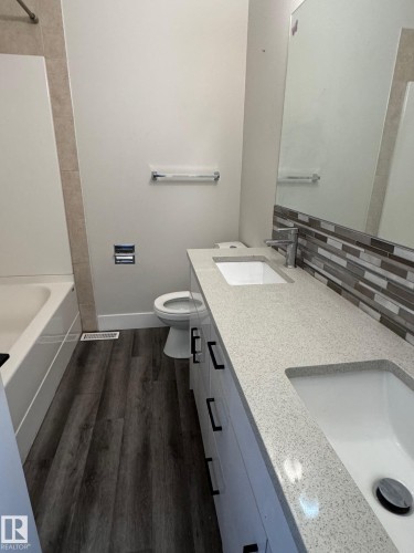 Bathroom featuring a double vanity with light-toned countertops, integrated sinks, and black hardware - 7604 7606 75 Street Nw, Edmonton, AB - Indoor Photo Showing Bathroom