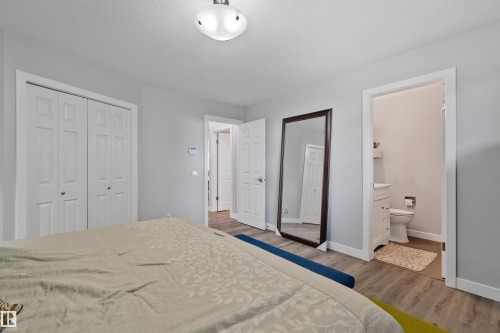 Light wood-finish flooring, white bi-fold closet doors, and a flush mount ceiling light fixture - 18812 89 Avenue Nw, Edmonton, AB 