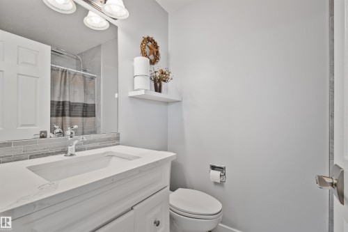Vanity with an integrated sink and chrome faucet, mosaic tile backsplash, and overhead vanity lighting - 18812 89 Avenue Nw, Edmonton, AB 
