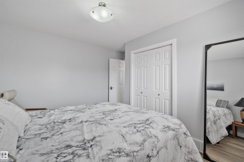 Wood-finish flooring, white paneled bifold closet doors, and a ceiling-mounted light fixture - 18812 89 Avenue Nw, Edmonton, AB 