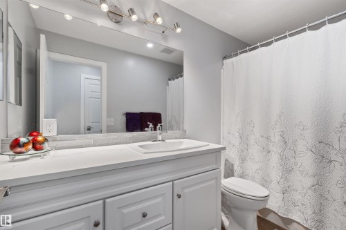 White vanity with panel-front cabinetry, integrated sink, and track lighting - 18812 89 Avenue Nw, Edmonton, AB 