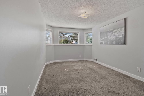 Recessed bay windows with blinds, light gray wall paint, textured ceiling, and gray carpet flooring - 18812 89 Avenue Nw, Edmonton, AB 
